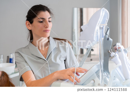 Female cosmetologist preparing LED mask machine in 124111588