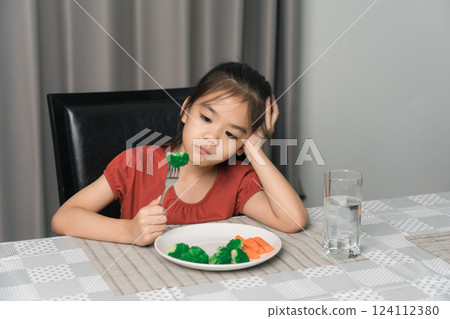 Little cute kid girl refusing to eat healthy vegetables. Children do not like to eat vegetables. Little cute kid girl refusing to eat healthy vegetables. Children do not like to eat vegetables. 124112380