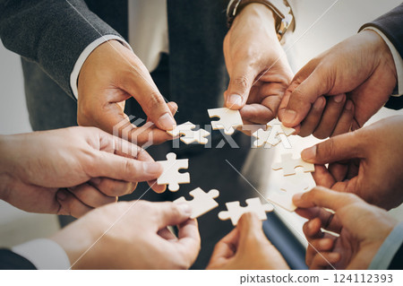 The concept of teamwork and partnership. Businessman's hands putting together puzzle pieces in the office and join together in a jigsaw puzzle team. Charity. Volunteers. Business unity as a team. The concept of teamwork and partnership. Businessman's hands putting together puzzle pieces in the office and join together in a jigsaw puzzle team. Charity. Volunteers. Business unity as a team. 124112393
