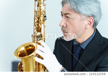 A man performing maintenance on a saxophone A man performing maintenance on a saxophone 124112559