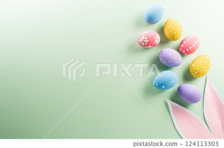 Easter party concept. Top view of easter bunny ears and colorful eggs on pastel background with copyspace for the text. Easter party concept. Top view of easter bunny ears and colorful eggs on pastel background with copyspace for the text. 124113303