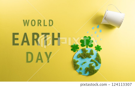 World environment day, earth day, save earth and eco concept. Concept of watering handmade globe from grass and paper on yellow background. 124113307