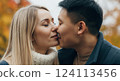 Romantic autumn kiss between young caucasian female and asian male in a park setting 124113456