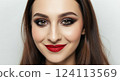 Confident young female with glamorous makeup and red lips against neutral background 124113569