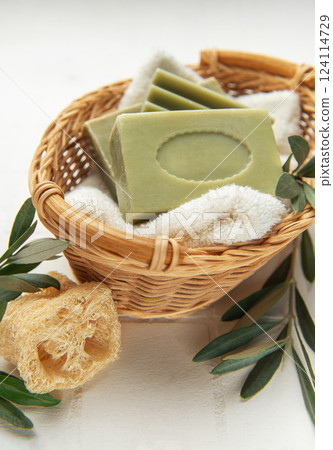 Olive soap bars resting on soft towel in wicker basket, embracing natural hygiene 124114729
