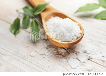Magnesium chloride flakes on wooden spoon with green leaves 124114734
