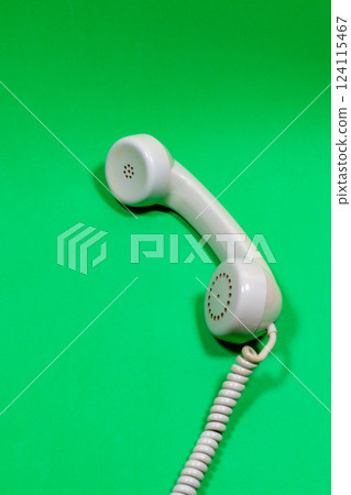 Gray handset of old telephone on a green surface Gray handset of old telephone on a green surface 124115467