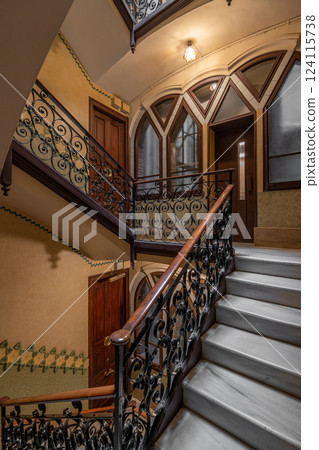 Spacious stairwell with curved wrought iron railings and elegant architectural features Spacious stairwell with curved wrought iron railings and elegant architectural features 124115738