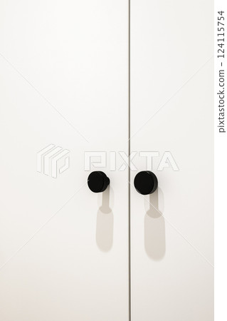 Close-up of modern black textured wardrobe handles on a white surface 124115754