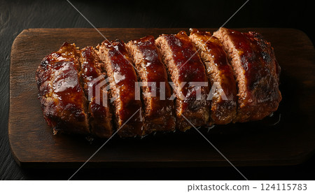Golden-Brown Glazed Meatloaf Sliced on a Dark Wooden Board 124115783