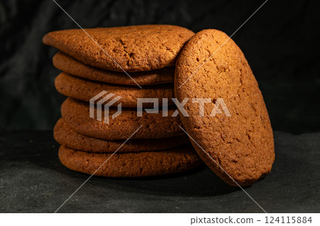 A stack of freshly baked chocolate cookies with a crispy texture and rich brown color, set against a dark background, perfect for dessert lovers 124115884