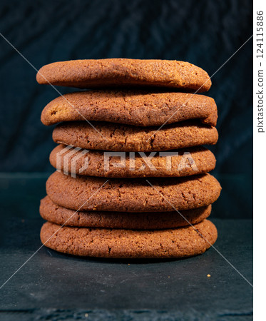 A stack of freshly baked chocolate cookies with a crispy texture and rich brown color, set against a dark background, perfect for dessert lovers 124115886