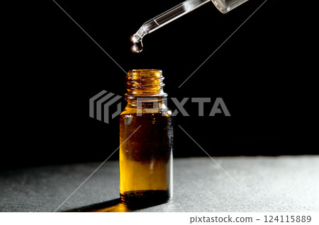 Essential oil dropper. Brown bottle. Dark background. Close-up. Health, beauty, wellness concept. 124115889