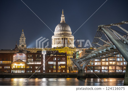 Pedestrians walk along the Millennium Bridge at night, with St. Paul's Cathedral illuminated in the background, creating a captivating urban scene over the River Thames in London. Pedestrians walk along the Millennium Bridge at night, with St. Paul's Cathedral illuminated in the background, creating a captivating urban scene over the River Thames in London. 124116075