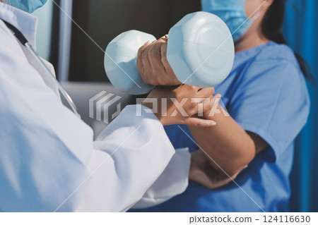 Asian caregiver woman or nurse training senior woman lifting dumbbell for arm exercise while therapy and rehabilitation in living room at home, caretaker or physiotherapist helping elderly workout. Asian caregiver woman or nurse training senior woman lifting dumbbell for arm exercise while therapy and rehabilitation in living room at home, caretaker or physiotherapist helping elderly workout. 124116630