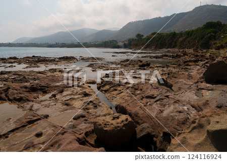 Coastal Landscape with Rocky Shoreline and Distant Hills 124116924