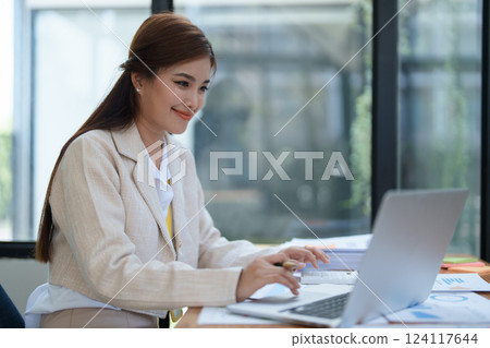 professional businesswoman planning and analyzing marketing charts and financial documents with a laptop and calculator papers on the desk professional businesswoman planning and analyzing marketing charts and financial documents with a laptop and calculator papers on the desk 124117644