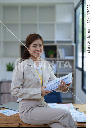 professional businesswoman planning and analyzing marketing charts and financial documents with a laptop and calculator papers on the desk professional businesswoman planning and analyzing marketing charts and financial documents with a laptop and calculator papers on the desk 124117652