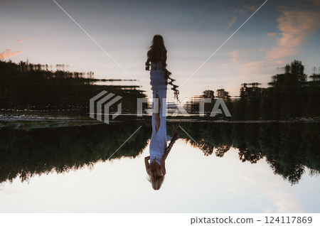 Reflective Evening with Woman Standing in Calm Lake 124117869