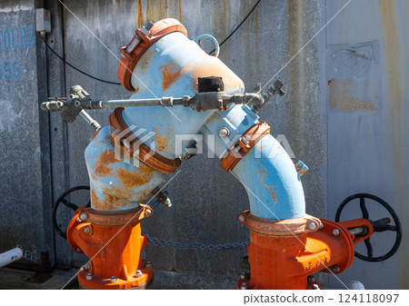 Rusty industrial water pipes with valves and connectors in an urban setting 124118097
