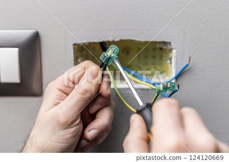 Electrician installing connector block into electrical wires using a screwdriver Electrician installing connector block into electrical wires using a screwdriver 124120669