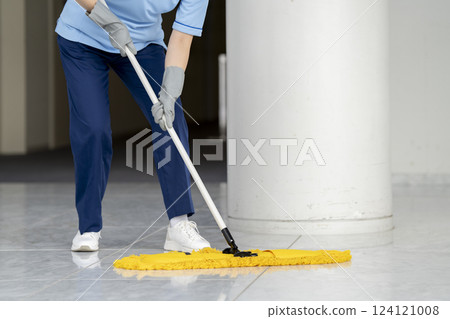 Building cleaning image: The hands of a female cleaning staff member wiping the floor with a mop 124121008