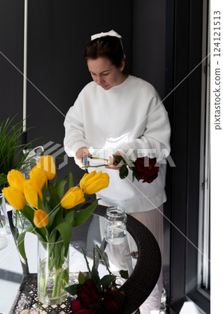Flower arranging activity in a modern kitchen with tulips and roses during daylight hours Flower arranging activity in a modern kitchen with tulips and roses during daylight hours 124121513