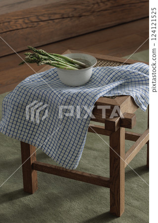Fresh asparagus in ceramic bowl on rattan stool with linen tea towel. Healthy lifestyle concept 124121525