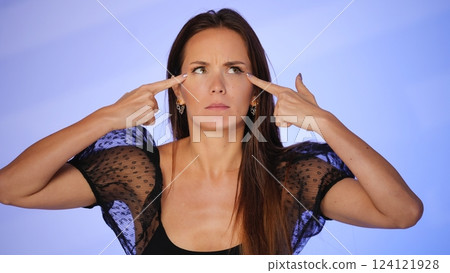 Beauty blogger pointing at under-eye wrinkles  124121928