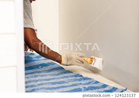Painter hands with gloves painting the wall with brush. Painter hands with gloves painting the wall with brush. 124123137