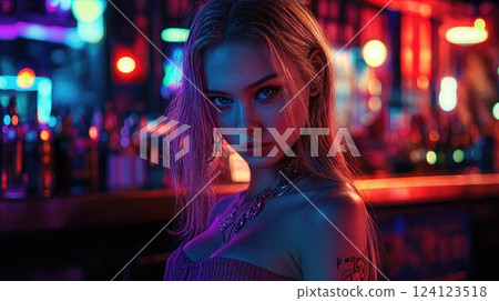 A woman dressed in a vibrant pink dress is standing in a bar at night 124123518