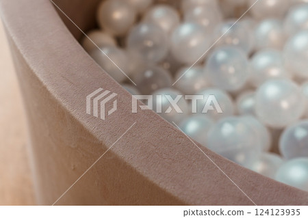 Close-Up View of Beige Velvet Play Pit Filled with Translucent Plastic Balls 124123935