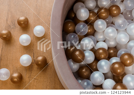 Overhead View of Brown, White, and Transparent Plastic Balls in Kids Play Pit on Wooden Floor 124123944