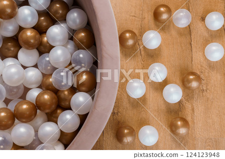 Decorative Golden, White, and Transparent Plastic Balls Scattered from a Ball Pool on Wooden Floor Decorative Golden, White, and Transparent Plastic Balls Scattered from a Ball Pool on Wooden Floor 124123948