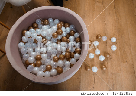 Stylish Beige Play Pool Filled with Gold, White, and Transparent Balls on Wooden Floor Stylish Beige Play Pool Filled with Gold, White, and Transparent Balls on Wooden Floor 124123952