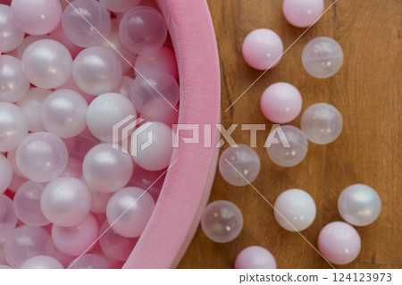Soft Pastel Colored Plastic Balls in Pink Ball Pit on Wooden Surface Soft Pastel Colored Plastic Balls in Pink Ball Pit on Wooden Surface 124123973