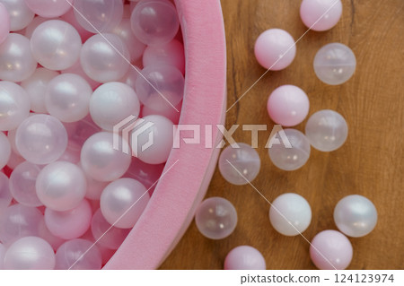 Soft Pink and White Plastic Balls in Velvet Pool on Wooden Background 124123974