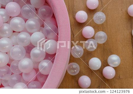 Pastel Pink and White Plastic Balls in Soft Pink Container on Wooden Floor Pastel Pink and White Plastic Balls in Soft Pink Container on Wooden Floor 124123976