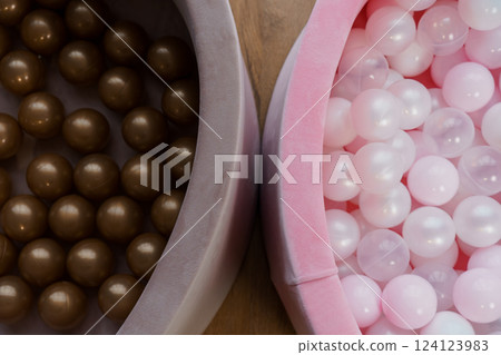 Top View of Two Colorful Children's Ball Pit Filled With Shiny Brown and Shimmering White Plastic Balls on Wooden Floor 124123983