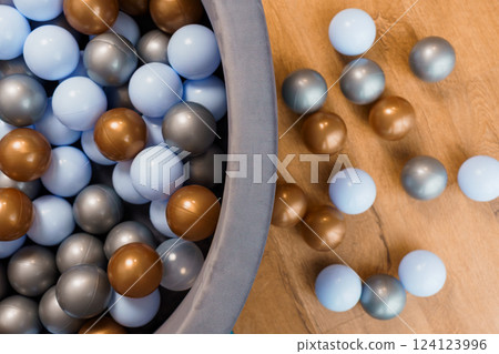 Close-up of Playful Multicolor Plastic Balls in Grey Container on Wooden Surface Close-up of Playful Multicolor Plastic Balls in Grey Container on Wooden Surface 124123996