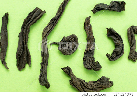 Large leaf black tea rolled leaves of different shapes, top view macro 124124375