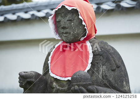 戴著紅色頭巾的地藏菩薩像。石像。日本寺廟風景 戴著紅色頭巾的地藏菩薩像。石像。日本寺廟風景 124125258