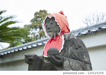 Jizo statue wearing a red hood. Stone statue. Scenery of a Japanese temple Jizo statue wearing a red hood. Stone statue. Scenery of a Japanese temple 124125259