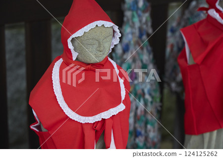 Jizo statue wearing a red hood. Stone statue. Scenery of a Japanese temple Jizo statue wearing a red hood. Stone statue. Scenery of a Japanese temple 124125262
