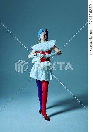 Woman in eccentric outfit standing confidently, red corset and sculptural skirt emphasizing blend of structured elegance and playful movement. Woman in eccentric outfit standing confidently, red corset and sculptural skirt emphasizing blend of structured elegance and playful movement. 124126230