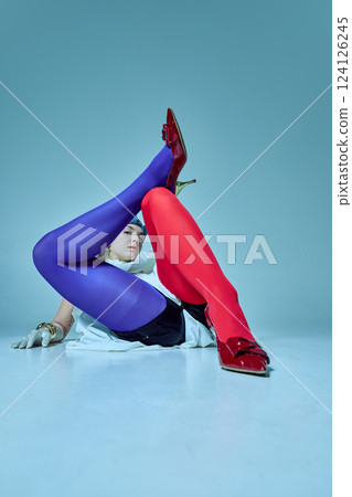 Playful yet powerful woman sitting on floor with legs crossed, dramatic heels and vintage-inspired costume creating visual tension. Playful yet powerful woman sitting on floor with legs crossed, dramatic heels and vintage-inspired costume creating visual tension. 124126245