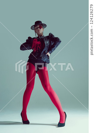 Woman in red tights and gothic jacket strikes a dominant pose, staring through heart-covered eye. Concept of fashion and style Woman in red tights and gothic jacket strikes a dominant pose, staring through heart-covered eye. Concept of fashion and style 124126279