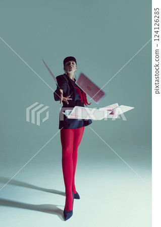 Young woman in black structured jacket, red tights, and heels dramatically throwing playing cards into air. Young woman in black structured jacket, red tights, and heels dramatically throwing playing cards into air. 124126285