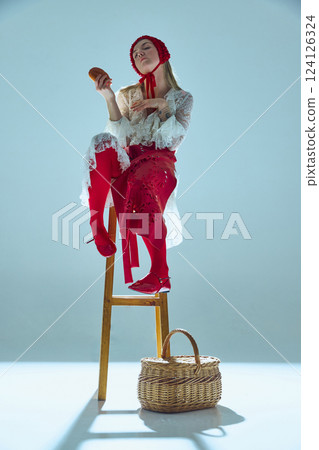 Young woman in white-red outfit perched on tall stool, tilting head with playful arrogance, holding bread like divine offering. Young woman in white-red outfit perched on tall stool, tilting head with playful arrogance, holding bread like divine offering. 124126324