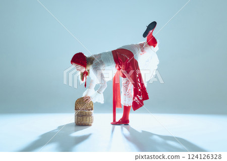 Elegant young woman balancing over basket in delicate motion, symbolizing fragile strength and poetic control of body. 124126328